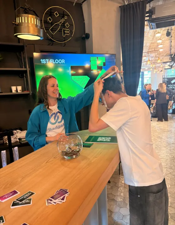 Staff member placing a BadgeMe lanyard over an attendee at the check-in desk
