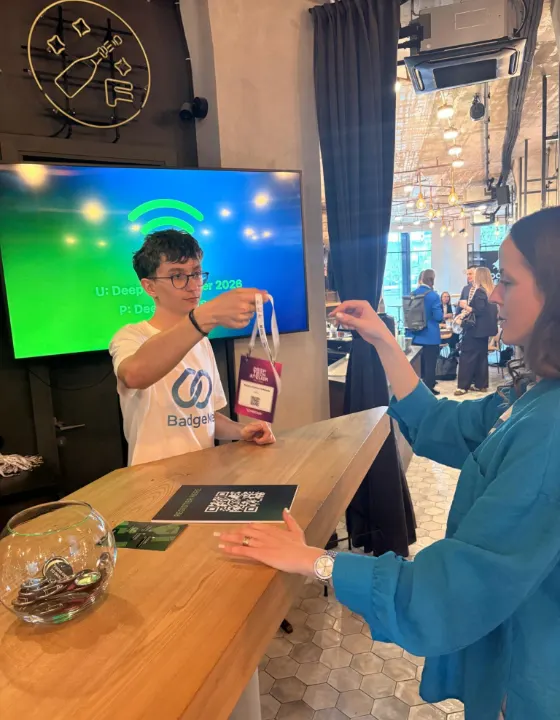 Staff member handing a printed badge across the check-in desk
